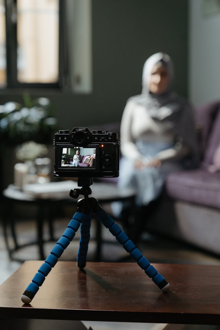 services-01 Camera on a tripod filming a woman in a cozy living room setting for a vlog.